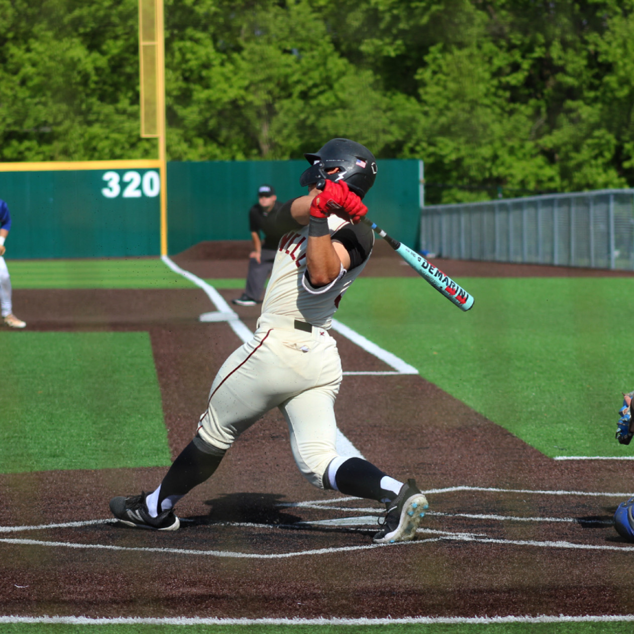 Justin George driving a baseball at the plate in a college game